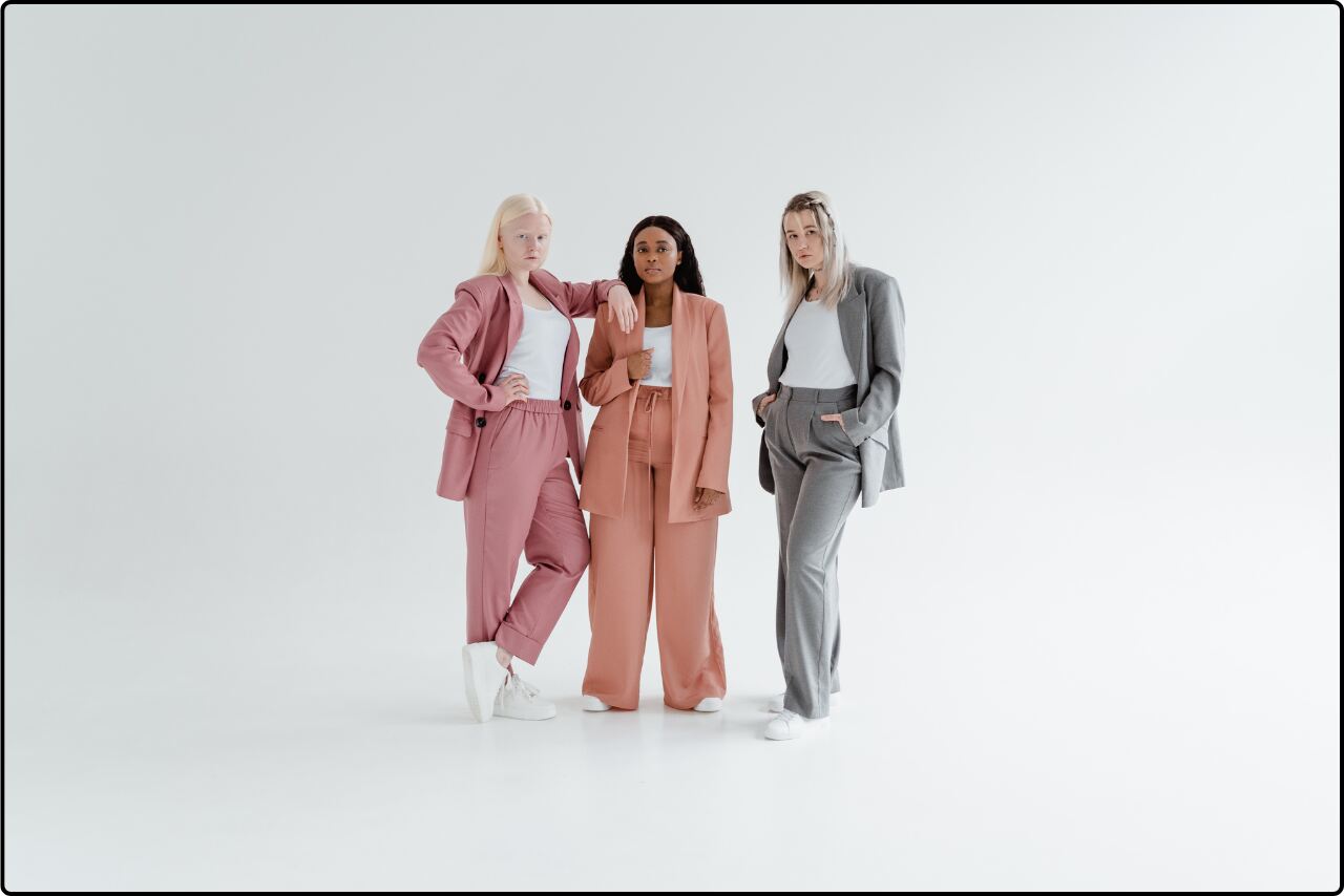 Group of professional women in corporate attire, standing together and smiling.